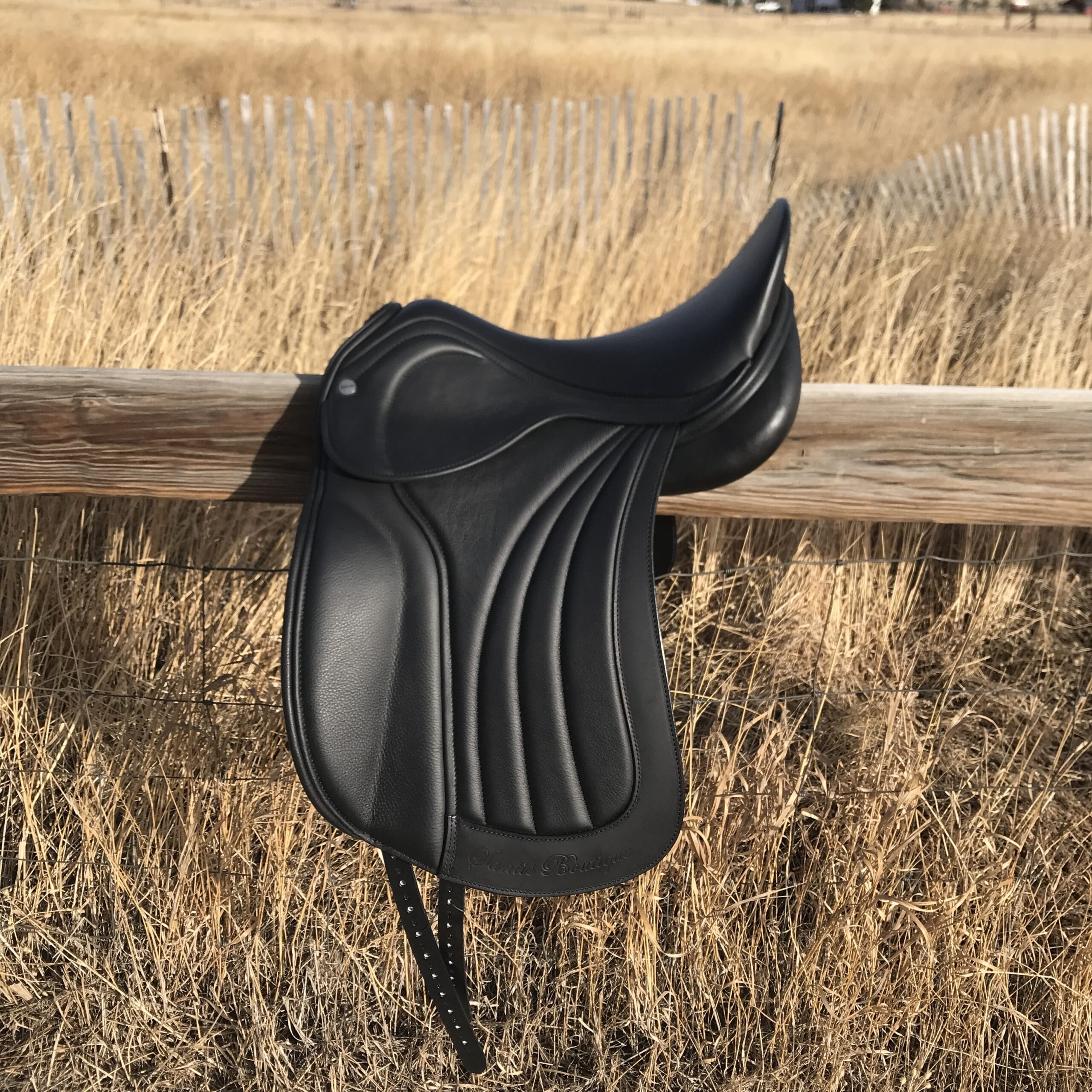 Keith Bryan Santis Boutique Dressage saddle on fence with field behind